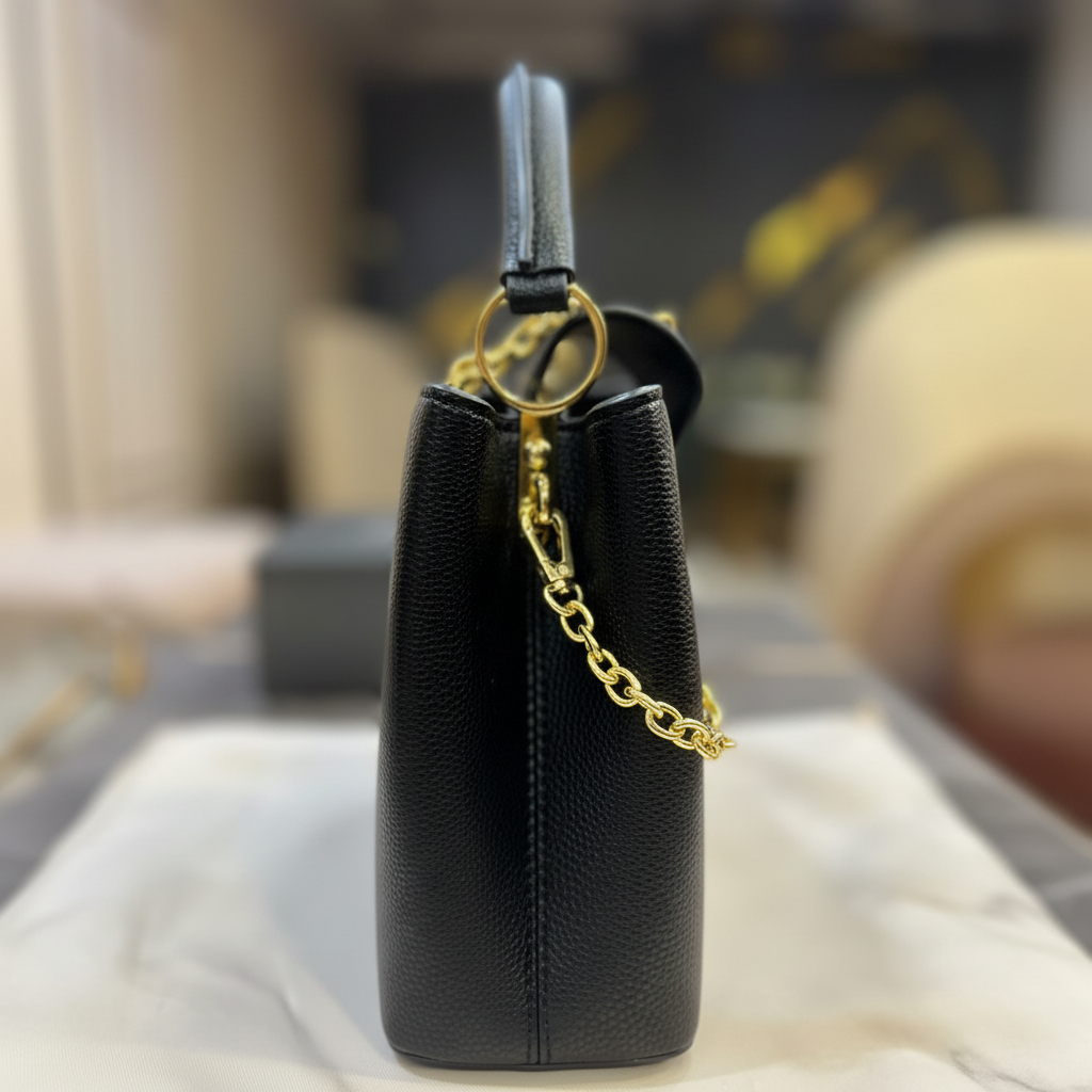 Louis Vuitton Capucines All Black side hardware detail on white marble