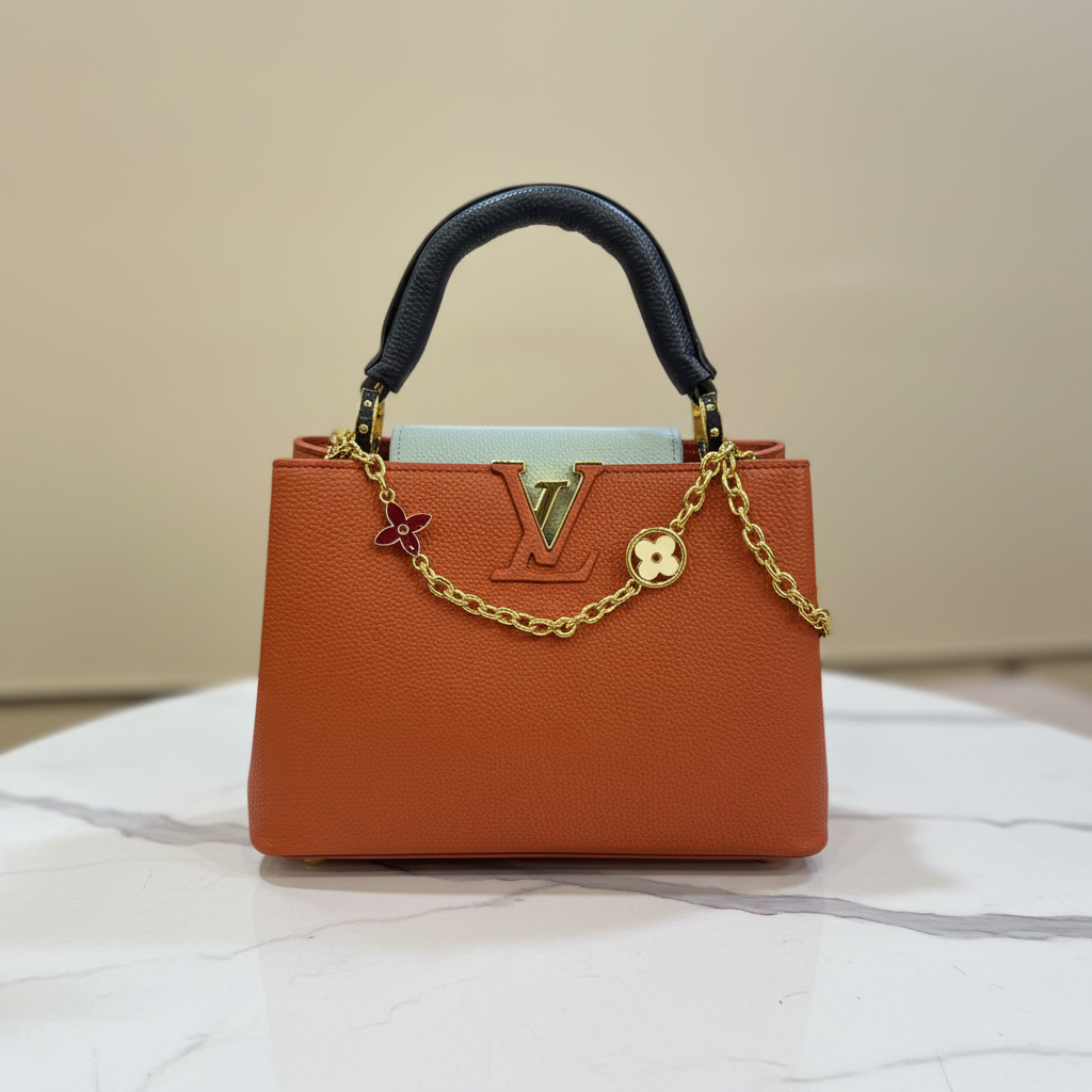 Louis Vuitton Capucines Orange Rust LV logo hardware front view on white marble
