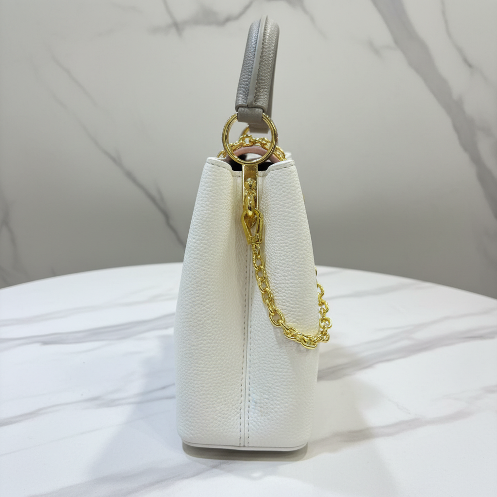 Louis Vuitton Capucines Cream White side hardware detail on white marble