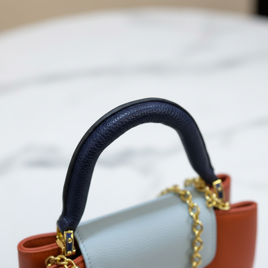 Louis Vuitton Capucines Navy Blue handle close-up on white marble